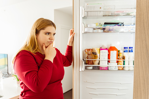 Beautiful body positive woman opened refrigerator bored eating